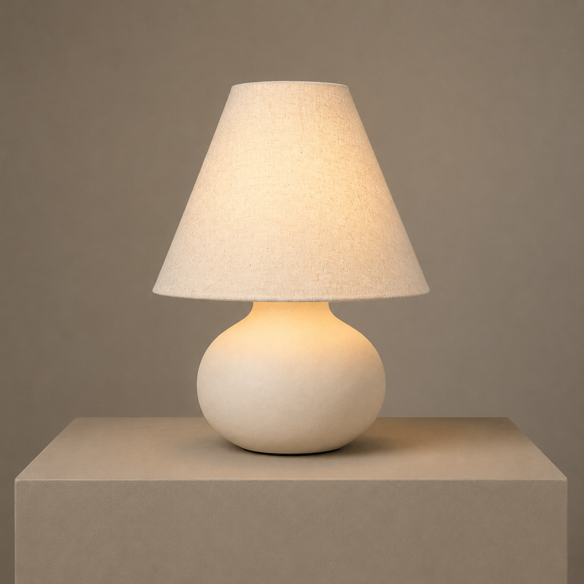 Illuminated ceramic table lamp with a white linen shade casting a soft warm glow.