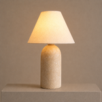 Illuminated sandstone table lamp with a linen shade casting a warm, soft glow.