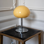 Sculptural cream glass lamp styled on a black marble side table against decorative white wall moulding.