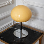 Sculptural cream glass shade with a glossy finish above a polished chrome lamp base.