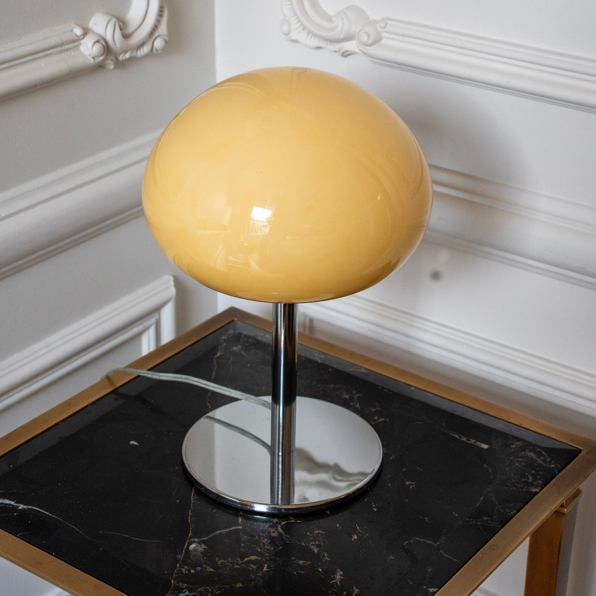 Sculptural cream glass shade with a glossy finish above a polished chrome lamp base.
