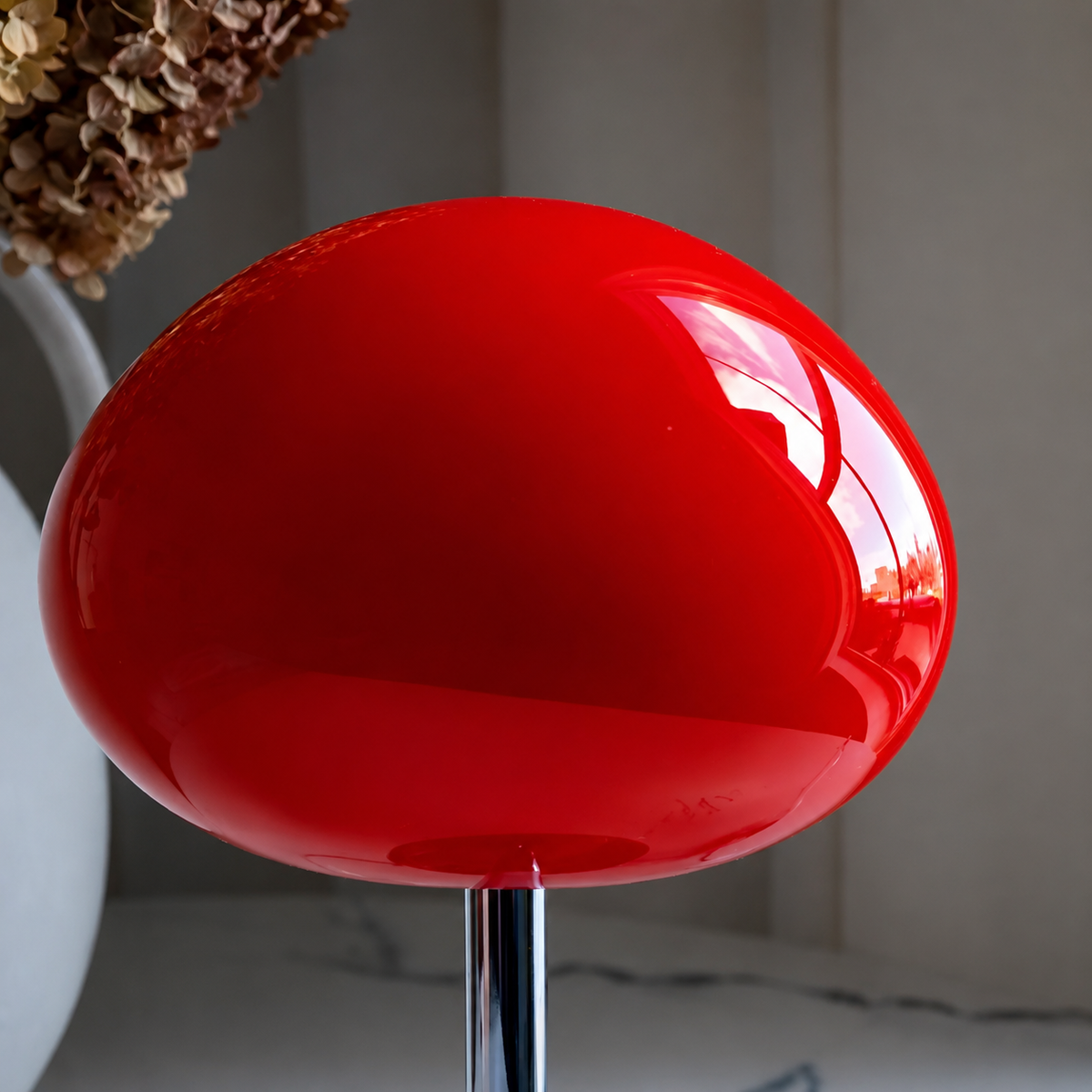 Close-up of the glossy red glass mushroom shade and polished chrome stem.