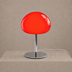 Illuminated red glass mushroom lamp casting a warm glow on a neutral pedestal.