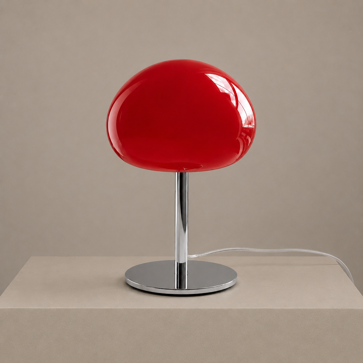 Red glass mushroom table lamp with a polished chrome stem and round base on a neutral studio backdrop.