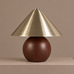Sculptural table lamp with a rounded woodgrain base and brushed brass cone shade on a neutral pedestal