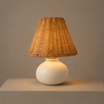Illuminated ceramic and rattan table lamp casting a warm glow through its woven shade.
