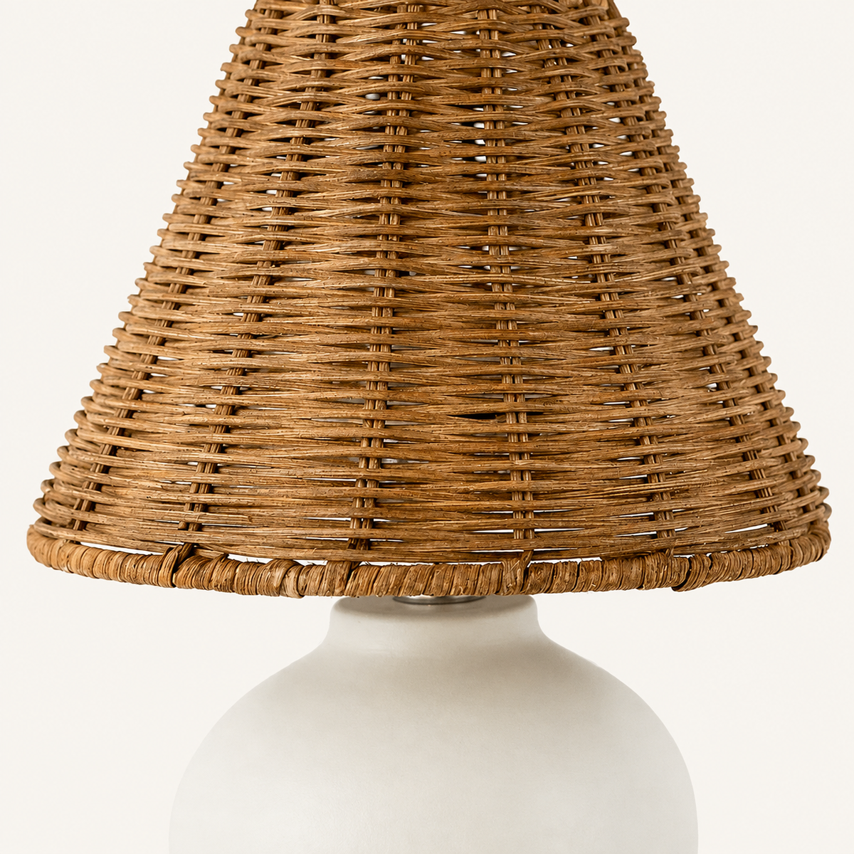 Close-up of the woven rattan lamp shade above a smooth rounded ceramic base.