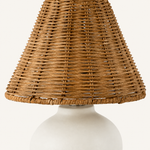 Close-up of the woven rattan lamp shade above a smooth rounded ceramic base.