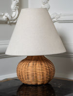 Small woven rattan lamp styled on a book against decorative white wall moulding.