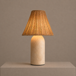 Illuminated rattan table lamp with a sandstone base casting a warm ambient glow.